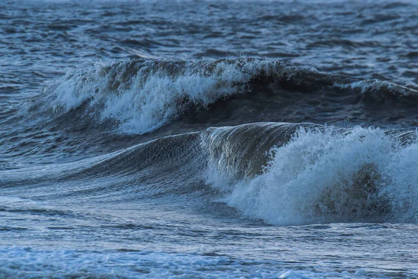 Sonbaharda fırtınalı ve güneşli bir günde Ouddorp köyü yakınlarındaki Hollanda sahillerine köpüklü dalgalar vuruyor.