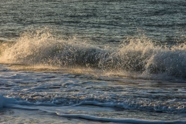 Güneş ışığı, sonbaharda Goeree Overflakkee adasının Northsea sahilindeki dalgaların yansımasına yansıyor.