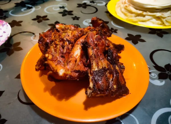 Indian style cooked Grilled chicken on a Orange coloured plate.