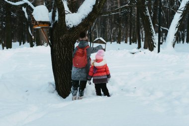 İnsanlar kuş yemliğine yemek koyuyor.