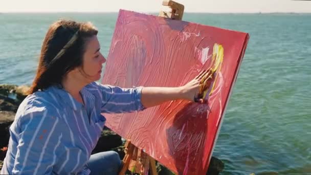 재능있는 화가는 강둑에 캔버스에 그림을 그립니다 손가락으로 아크릴 그림을 다채롭고 — 비디오
