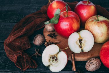 Tahtada, tahta üzerinde olgun bir bahçe elması. Bir elma ikiye bölündü. Yanında fındık, anason, tarçın var. Durgun hayat. Boşluğu kopyala.