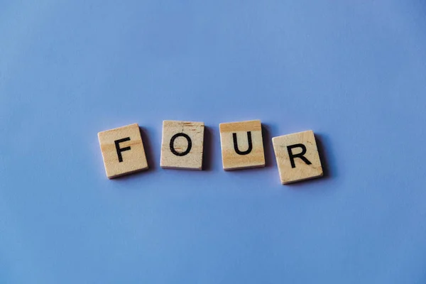 Номер Четыре Выложен Словами Плитки Деревянные Плитки Синем Фоне Буквами — стоковое фото