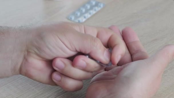 Close-up mannen handen, haalt pillen met medicijnen uit een blisterverpakking — Stockvideo