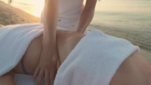 Dívka masáž terapeut na břehu moře dělá břicho masáž na ženu. — Stock video