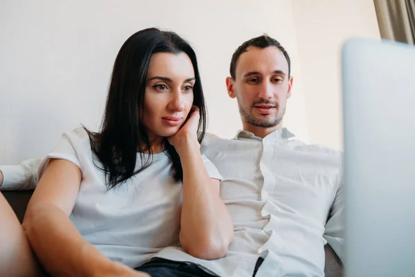 Чоловік і дружина, чоловік і жінка сидять на дивані вдома, використовуючи ноутбук — стокове фото