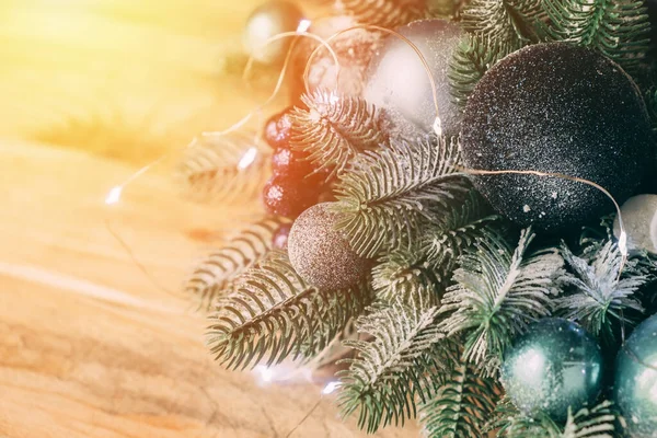 Noel süsü. Yakın plan bir Noel çelenginin parçası. Tahta bir masanın üzerinde ışıklar ve toplar olan Noel ağacı dalı.