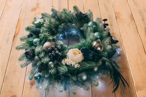 El yapımı Noel çelengi ahşap bir kapıya asılı. Çelenk, çelenklerle aydınlatılıyor, yakın plan görüntü. Mutlu Noeller.