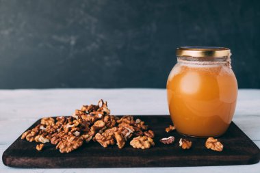 Cam kavanoz bal, mutfak masasında ceviz ve beyaz masa. Soyulmuş fındık.