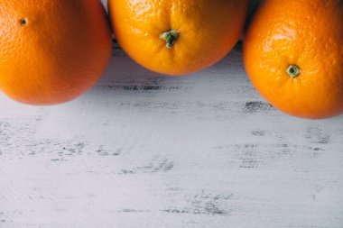 Top view on a white wooden table and three tangerines lying on top. Copy space