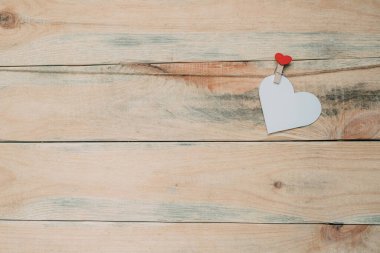 Küçük karton kalp çamaşır iğnesiyle bağlanmış ipe asılı..