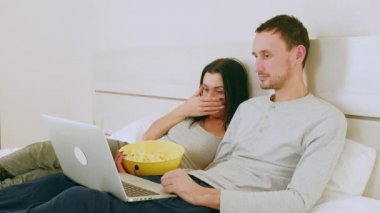 Akşamları genç evli Avrupalı çift evde dizüstü bilgisayar kullanarak korku filmi izliyor. Kız korkuyla yüzünü kapatır, erkek biraz arkasını döner..