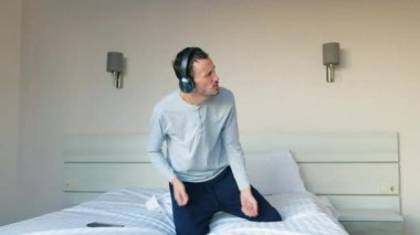 Kulaklıklı genç adam en sevdiği müziği akıllı telefonuyla açar ve yatakta dans etmeye başlar. Mutlu adam evde en sevdiği şarkıyla dans eder..