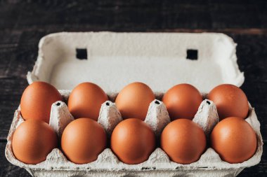 Tahta masadaki açık bir karton kutuda düzinelerce tavuk kahverengi yumurta..