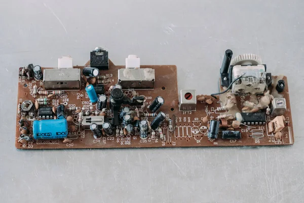 Metal bir masanın üzerinde çalışmayan eski bir mikro devre. Elektrik ekipmanlarının sökülmesini onar.