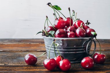 Masadaki dekoratif metal kasede bir demet olgun kiraz. Boşluğu kopyala.