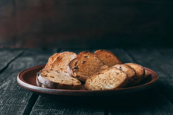 Dilimlenmiş kuru, pişmiş ekmek ve kil tabakta kuru üzüm. Çay ya da kahve için lezzetli, beyaz ekmek..