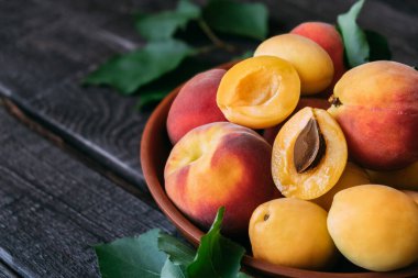 Composition of pineapple variety apricot and peaches in a clay plate on dark wooden background. Top view close-up.