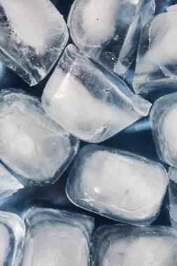 Mavi arka planda cam bir kasede buz küplerinin üst görüntüsü