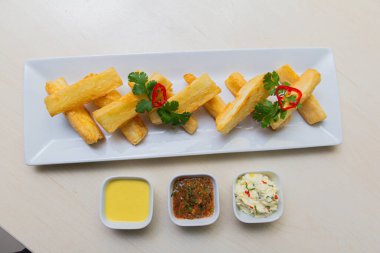 Kızarmış yuccas, baharatlı sarsa ve mayonez ile servis edilir..