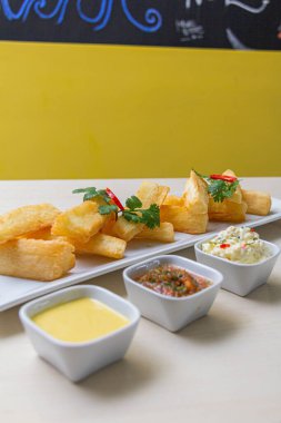 Kızarmış yuccas, baharatlı sarsa ve mayonez ile servis edilir..