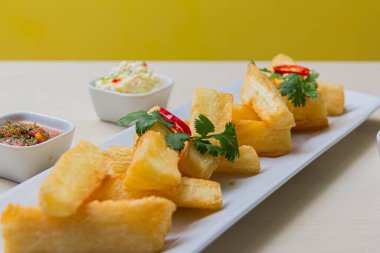 Kızarmış yuccas, baharatlı sarsa ve mayonez ile servis edilir..