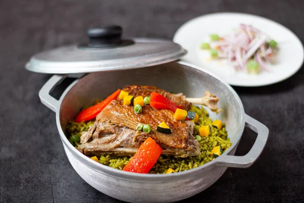 Arroz con pato, tipik bir Peru yemeği, gri arka planda bir tencerede.