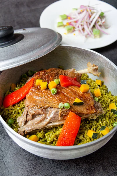 Arroz con pato, tipik bir Peru yemeği, gri arka planda bir tencerede.