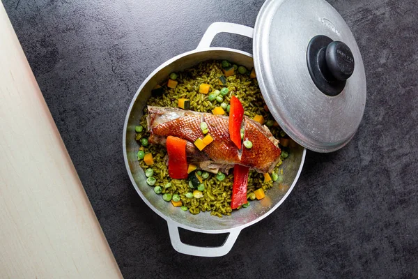 Arroz con pato, tipik bir Peru yemeği, gri arka planda bir tencerede.
