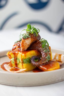 Katran ve avokadoyla doldurulmuş Causa, sosla yıkanmış ahtapot dilimleri..