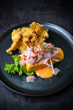 Kızarmış balıkların eşlik ettiği Causa acevichada..