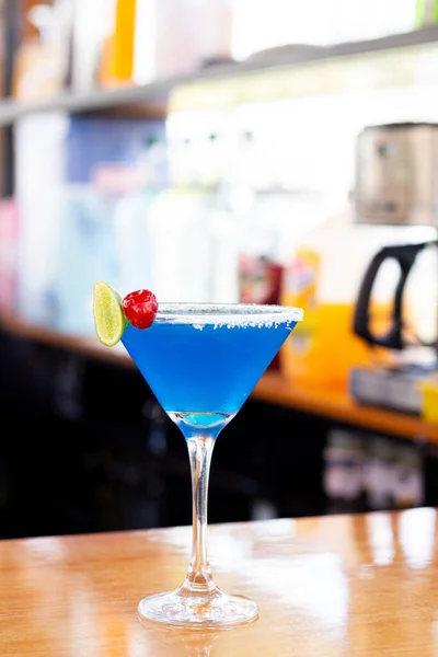 Limon dilimi ve biberiye filizi serpiştirilmiş bar arka planıyla süslenmiş buzlu, soğuk modern gurme cin ve tonik karışımı.