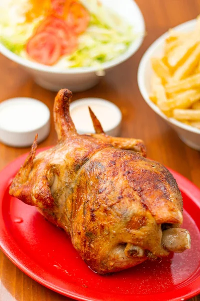 Grilled chicken with french fries on a wooden table.