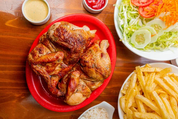 Grilled chicken with french fries on a wooden table.