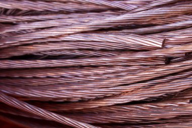 Turuncu ve pembe bakır kablolar birbirine dolanmış ve karmakarışık. Bakır renkli kablolar ve liflerin soyut dokusu.