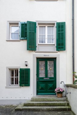 Avrupa 'nın eski bir kasabasında, koyu yeşil ahşap panjurlu ve camlı kapılı güzel beyaz bir apartman dairesi..