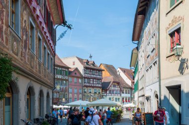 İsviçre 'nin turistik kenti Stein am Rhein' de yazın güneşli bir tatil gününde tarihi cadde, turistler, dükkanlar ve İsviçre bayrakları görülüyor. 