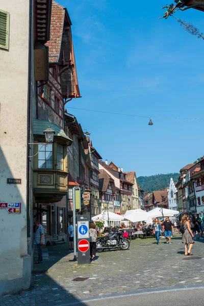 İsviçre 'nin turistik kenti Stein am Rhein' de yazın güneşli bir tatil gününde tarihi cadde, turistler, dükkanlar ve İsviçre bayrakları görülüyor. 
