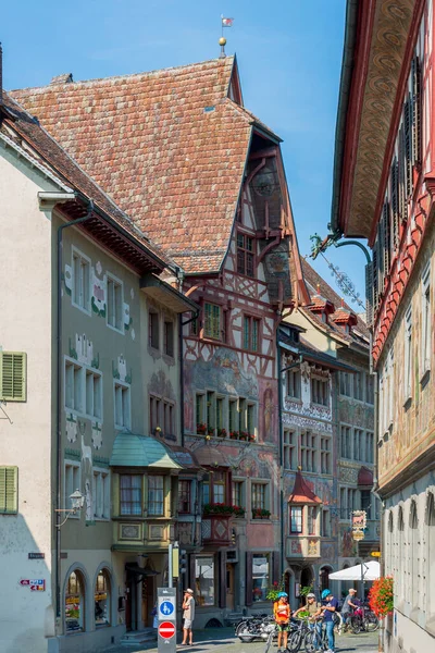 İsviçre 'nin turistik kenti Stein am Rhein' de yazın güneşli bir tatil gününde tarihi cadde, turistler, dükkanlar ve İsviçre bayrakları görülüyor. 