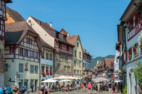 İsviçre 'nin turistik kenti Stein am Rhein' de yazın güneşli bir tatil gününde tarihi cadde, turistler, dükkanlar ve İsviçre bayrakları görülüyor. 