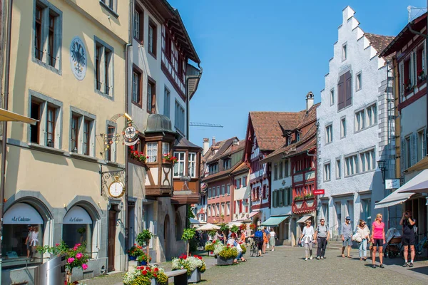 İsviçre 'nin turistik kenti Stein am Rhein' de yazın güneşli bir tatil gününde tarihi cadde, turistler, dükkanlar ve İsviçre bayrakları görülüyor. 