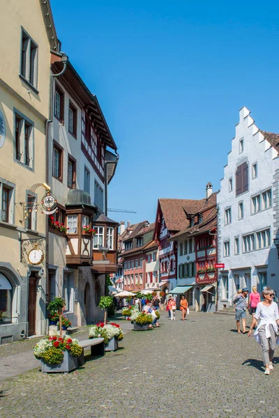 İsviçre 'nin turistik kenti Stein am Rhein' de yazın güneşli bir tatil gününde tarihi cadde, turistler, dükkanlar ve İsviçre bayrakları görülüyor. 