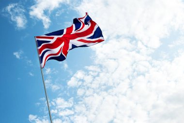 Büyük Britanya bayrağı mavi gökyüzünde rüzgarda dalgalanıyor.