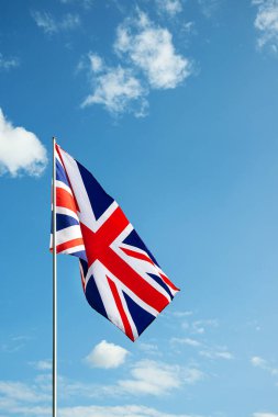 Büyük Britanya bayrağı mavi gökyüzünde rüzgarda dalgalanıyor.