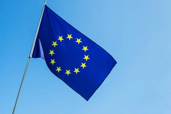 유럽 연합 (EU) 국기가 푸른 하늘 위에서 바람에 흔들리고 있다 스톡 사진