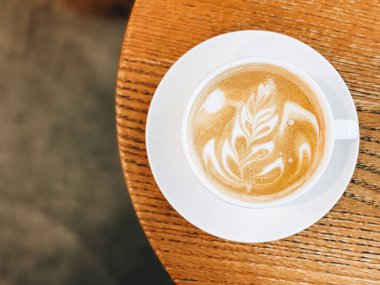 Beyaz seramik bardakta taze cappuccino kahvesi ahşap masada fotokopi alanı olan..
