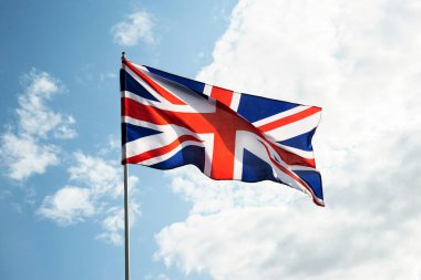 Büyük Britanya bayrağı mavi gökyüzünde rüzgarda dalgalanıyor.