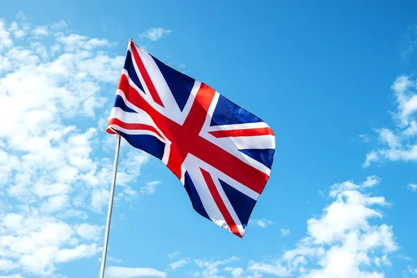 Büyük Britanya bayrağı mavi gökyüzünde rüzgarda dalgalanıyor.