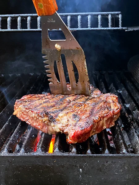 Жареное мясо барбекю стейк на горящем гриль барбекю с дымом. — стоковое фото