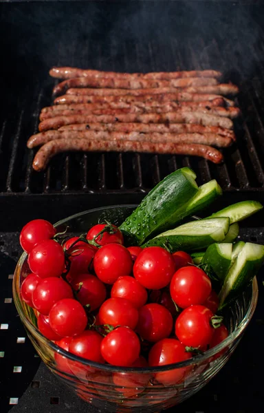Roasted sausages cooking on flaming grill barbecue and vegetables. — стоковое фото